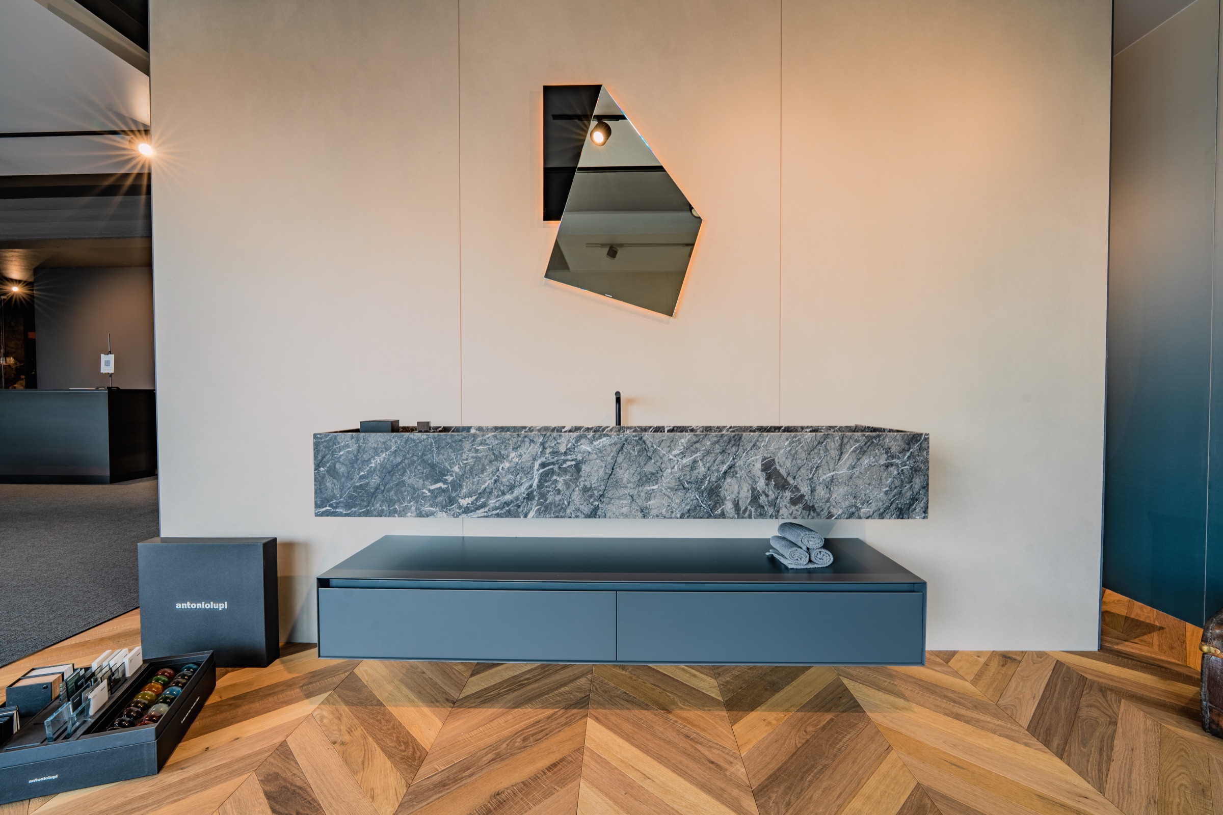 Bagno espositivo con marmo grigio e parquet a spina italiana