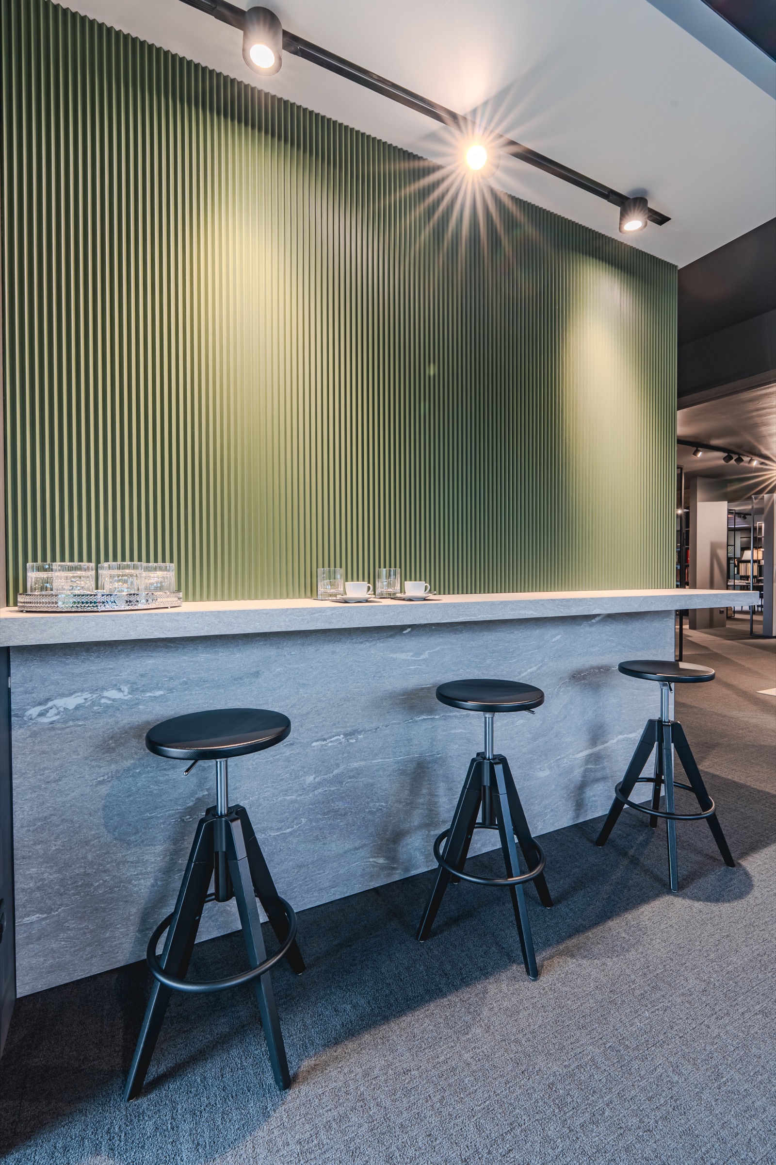 Area cucina dello showroom con parete a doghe verdi