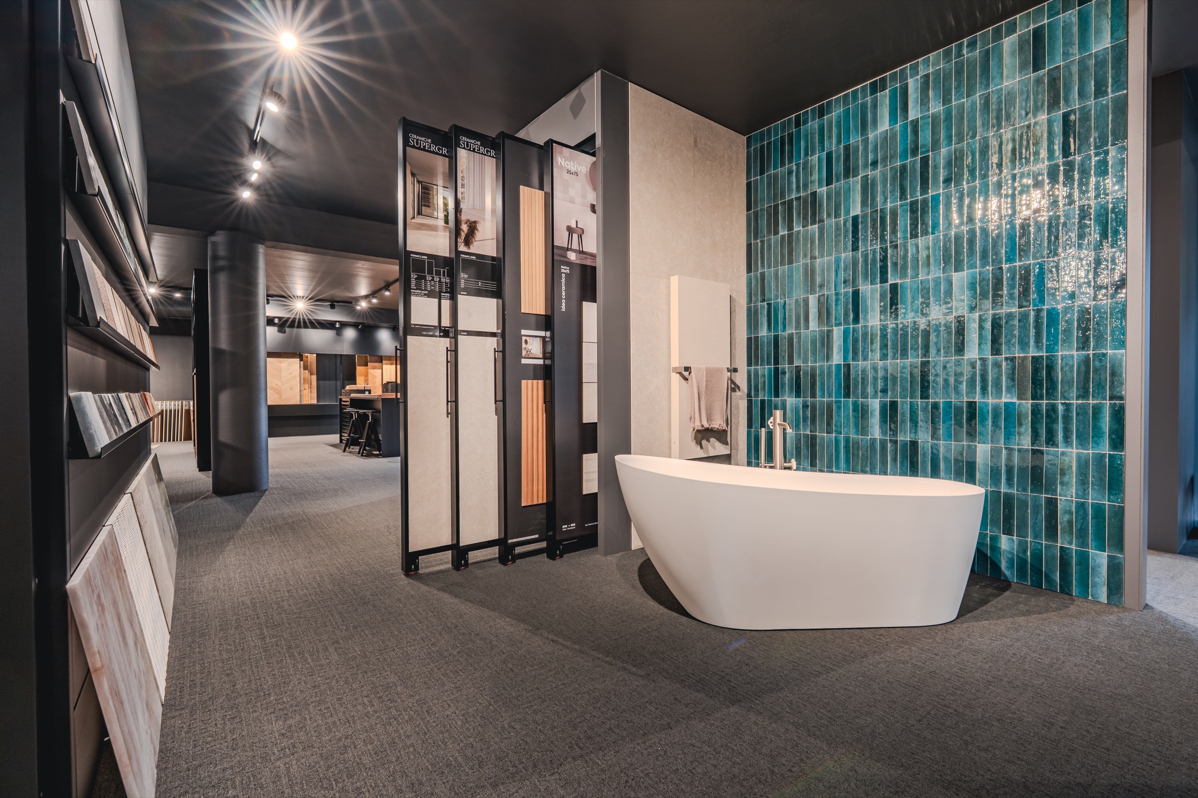 Bagno espositivo con vasca freestanding e parete in mosaico turchese